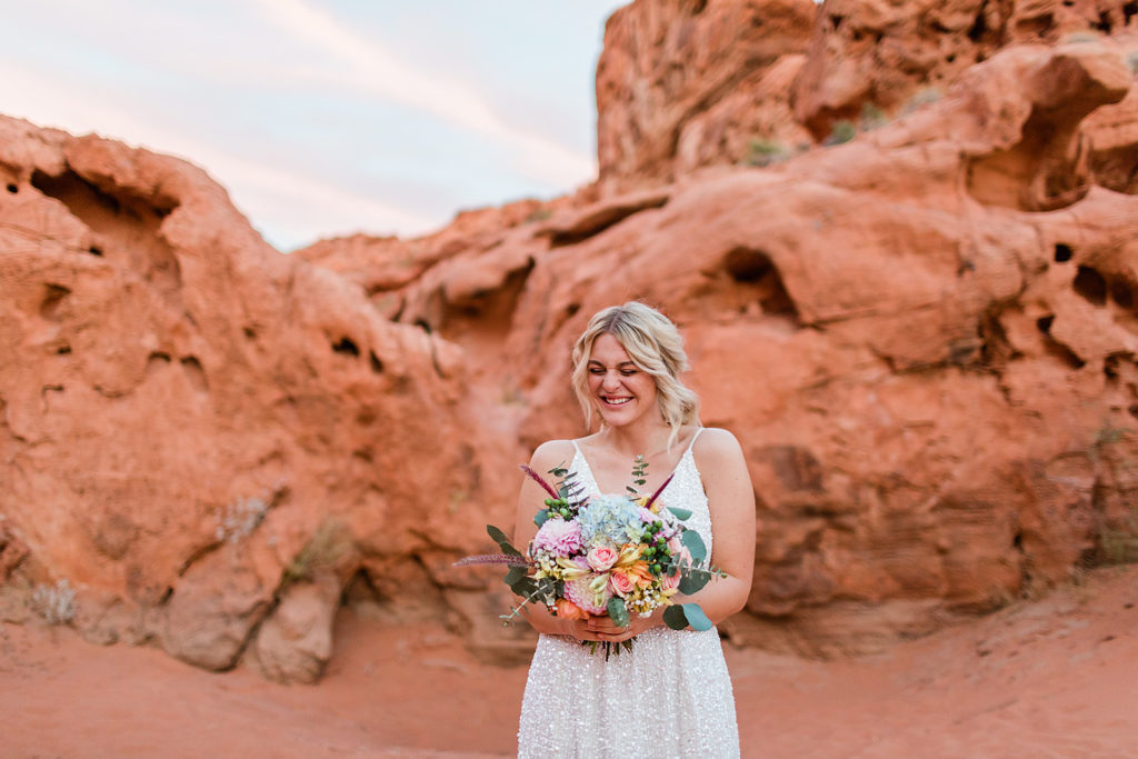 an image of a bride smiling and holding her bouquet at her elopement at Valley of Fire