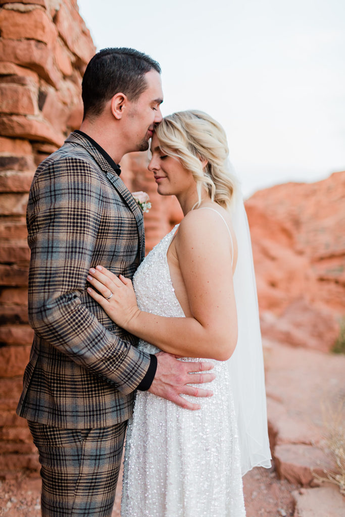groom kissing his bride gently on the forehead at their elopement at Valley of Fire